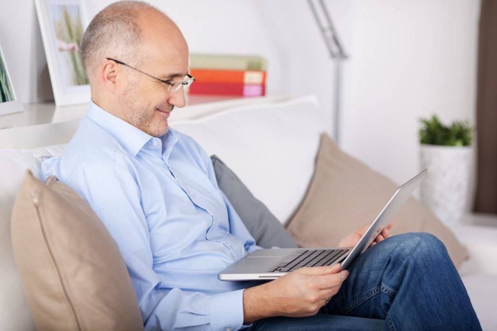 21145760 - smiling senior man browsing the internet in the living room ...