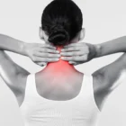 Black and white photo of a woman holding the back of her neck, that's radiating pain due to complications from Arthritis