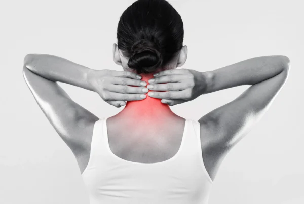 Black and white photo of a woman holding the back of her neck, that's radiating pain due to complications from Arthritis