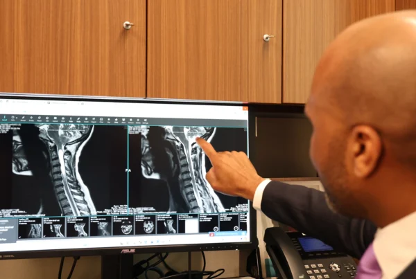 Dr. Moise Reviewing Scans of A Chiari Malformation patient, pointing at the Screen